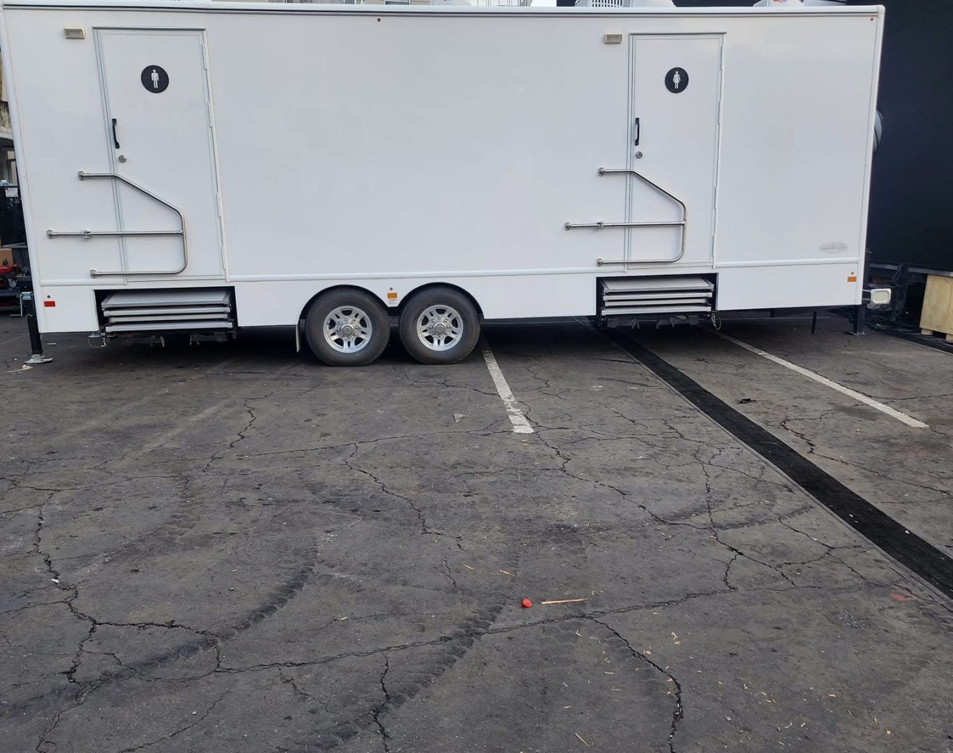 Experienced crew positioning portable restroom for safe access near active outdoor work area